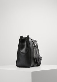 Borsa a tracolla in pelle nera con finitura testurizzata, dotata di dettagli in metallo argentato, accentuata da una catena e con tracolla regolabile. Vista laterale mostrata.