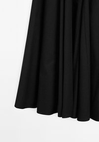 Gonna nera a campana realizzata in tessuto morbido, con pieghe e orlo senza cuciture che crea una silhouette fluida. Design semplice e minimalista.