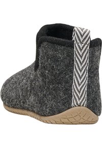 Chausson en laine gris foncé avec doublure intérieure noire, languette de talon gris et blanc à motif, et semelle extérieure en caoutchouc texturé marron clair.