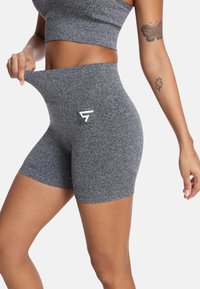 Šedé športové šortky s jemnou textúrou, vysokým pásom a bielym logom na prednej strane. Navrhnuté pre pohodlie a flexibilitu počas tréningov.