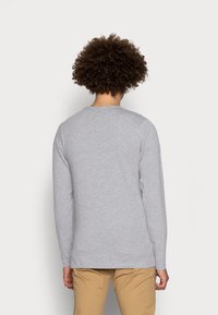 Gray long-sleeve t-shirt made of soft cotton with a round neck and a relaxed fit. Features stitched seams and a slightly curved hem.