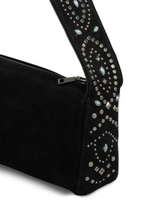 Czarna zamszowa torba z zapięciem na zamek, z mocno ozdobionym paskiem z srebrnymi ćwiekami i turkusowymi akcentami w wirującym wzorze.