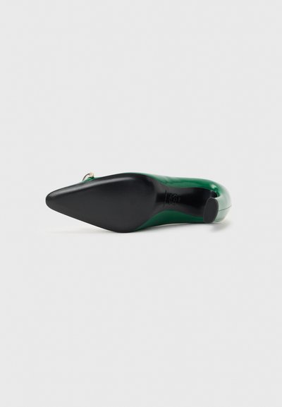 Πράσινο δερμάτινο γοβάκι με μυτερό άκρο και μαύρη σόλα, σε προβολή από τη πλευρά της σόλας, σε απλό ανοιχτό φόντο.