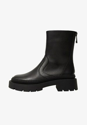 Bota de cuero negra hasta la mitad de la pantorrilla con suela gruesa y acanalada, puntera redondeada, cremallera lateral y detalles sutiles de costura.
