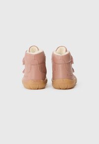Zapatos de charol rosa de caña alta con forro de felpa, correa de velcro y suela de goma flexible. Forma redondeada y textura suave con detalles de costura.