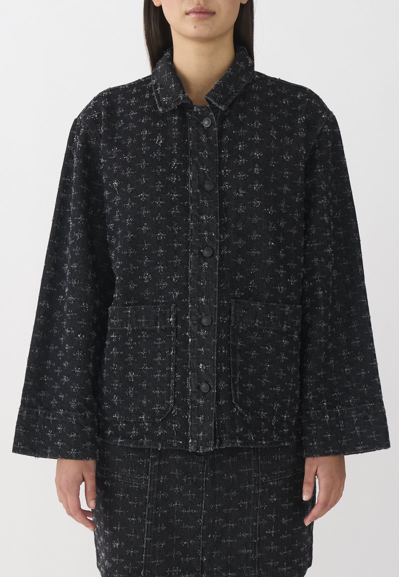 Schwarze Jeansjacke mit einem dezenten, sich wiederholenden Muster, mit einem Kragen, Knopfverschluss und zwei vorderen Taschen.