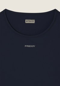 T-shirt bleu marine avec un col rond et des coutures plates. Présente un logo argenté "FREDDY" sur la poitrine. Matériau lisse et léger.
