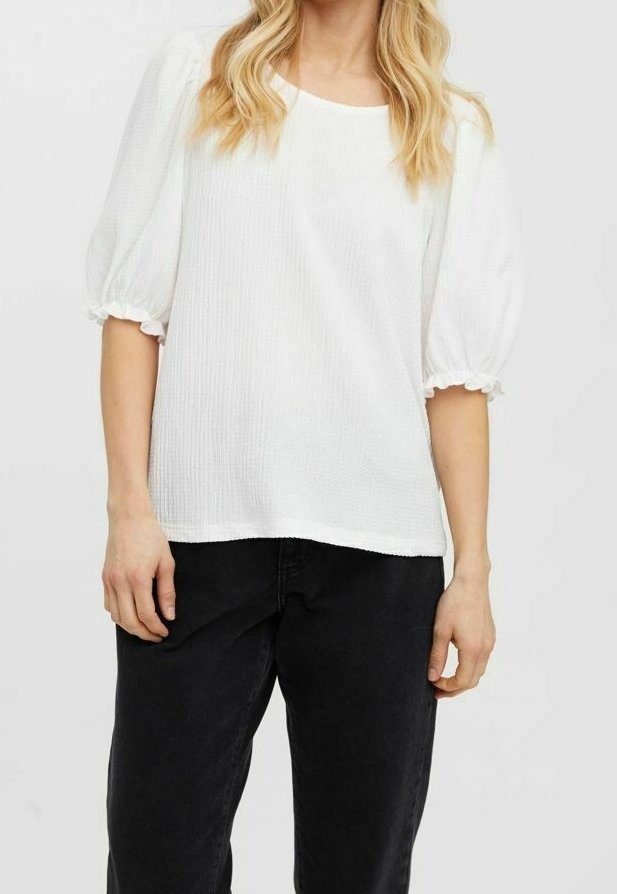 Vit, texturerad topp med korta puffärmar och rund halsringning, kombinerad med svarta byxor. Tyget verkar lätt och luftigt.