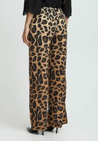 Pantalons larges en imprimé léopard beige et noir, avec un tissu doux, une taille élastique et un design fluide.