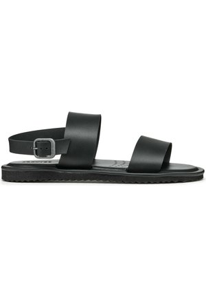 Sort flad sandal med to brede stropper over foden og en ankestropp med sølvspænde, tekstureret sål og polstret fodseng.