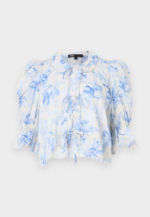 Blouse fleurie en crème avec des motifs de fleurs bleues, manches bouffantes, col et détail de cordon à l'avant. Tissu léger avec une finition lâche et texturée.