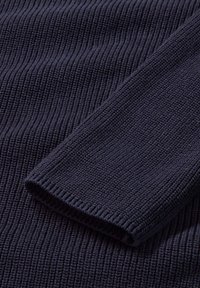 Dunkelblaue gerippte Strickware mit glatter Textur und einem umgeschlagenen Bündchen. Das Muster zeigt vertikale Linien, die durch das Stricken entstanden sind.