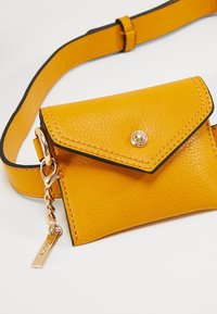 Borsa a tracolla gialla in pelle con superficie texture, pattina pieghevole, chiusura con bottone a pressione dorato e dettaglio in catena dorata.