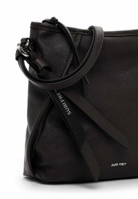 Černá kožená kabelka s texturou, nastavitelným popruhem, stříbrnou přezkou a logem "SURI FREY" na předním rohu.