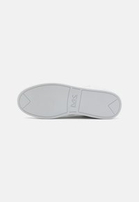 Semelle de chaussure en caoutchouc blanc avec une texture lisse. Présente un logo légèrement surélevé et un design segmenté pour améliorer l'adhérence et la flexibilité.