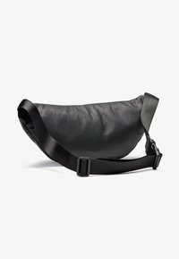 Borsa a tracolla nera in pelle con forma curvata. Presenta una superficie texturizzata e una tracolla piatta regolabile con una fibbia in plastica.