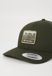 Green snapback cap, featuring a structured design, embroidered mountain patch, and textured fabric with a flat brim.