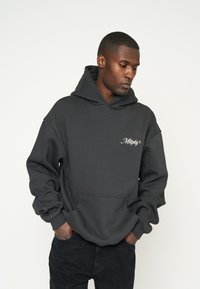 Houthskoolgrijze hoodie van zachte stof met een voorzak. Bevat een logo in lichte schrijfletters op de linkerkant van de borst. Ontspannen pasvorm, ruime capuchon.
