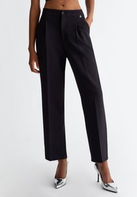 Pantaloni tailored neri con design a gamba dritta, caratterizzati da una texture liscia, chiusura con bottone singolo e un piccolo logo in evidenza.