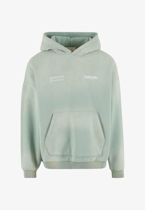 Gaiši zaļš kapuci džemperis ar kabatu, ribētām piedurknēm un apakšmalu. Tam ir baltā drukāta rakstība priekšpusē un mīksta, teksturēta virsma.