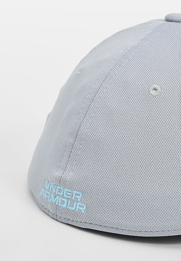 Gorra gris claro hecha de un tejido texturizado, con el logotipo bordado de "Under Armour" en azul claro en la parte delantera. Visera curva y forma estructurada.
