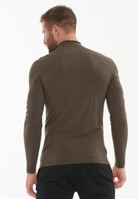 Langdurige bruin shirt met een aansluitend ontwerp, een gladde textuur en een hoge kraag, met platte naden en zonder zichtbare logo's.