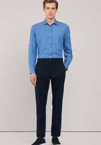 Lichtblauwe denimoverhemd met knopen, gecombineerd met donkerblauwe broek. Soepele textuur, getailleerde pasvorm en een eenvoudig design. Casual schoeisel inbegrepen.