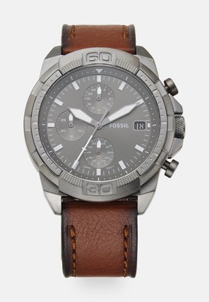 Montre Fossil avec un cadran gris, boîtier en acier inoxydable de couleur argent et bracelet en cuir marron. Elle possède des sous-cadrans chronographes et un affichage de la date.