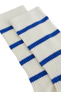 Balti medvilniniai kojinės su horizontaliais mėlynais dryžiais, pasižymi įribuota tekstūra ir įprasto ilgio dizainu. Patvari siuvimo technologija.