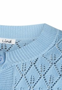 Pulover tricotat de culoare albăstruie, cu guler rotund, având un model delicat în formă de diamant și un buton albastru pe partea stângă. Eticheta spune "Lind".
