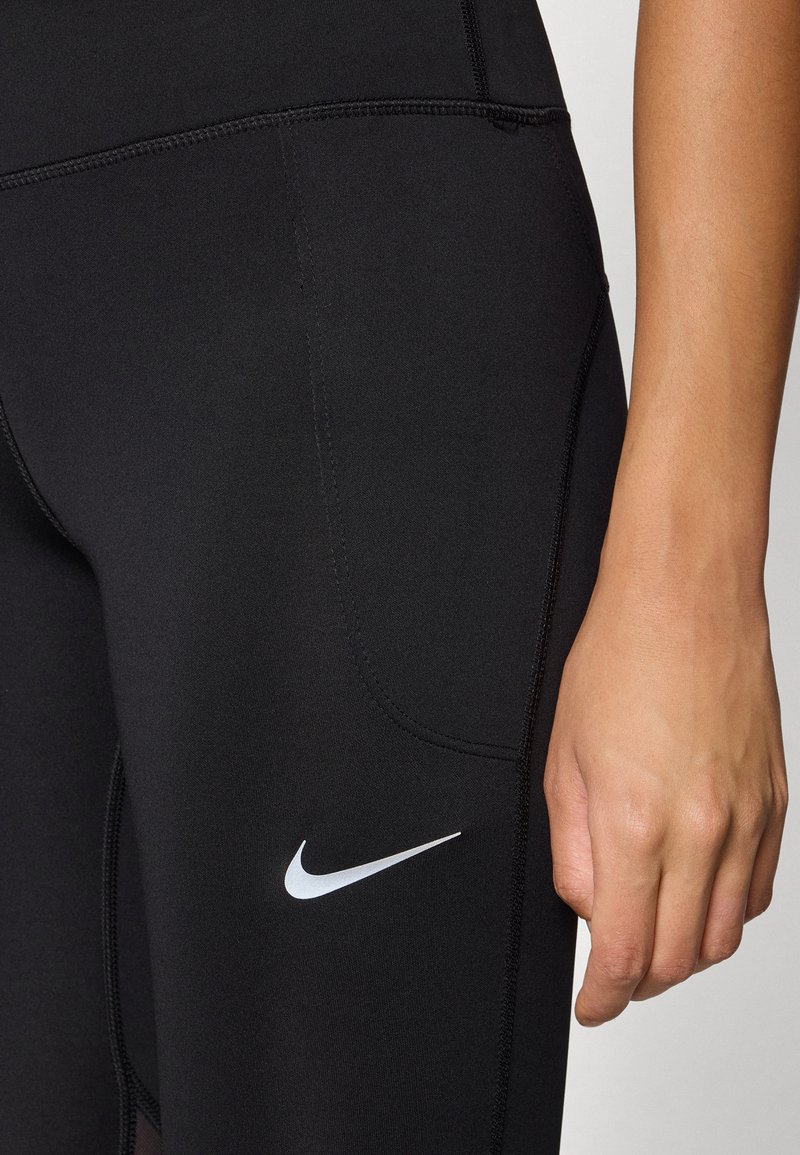 Leggings deportivos negros hechos de tela elástica, con un logo blanco de Nike, costuras planas y un diseño ajustado.