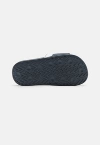 Suola di sandalo blu realizzata in un materiale gommoso nero testurizzato con un motivo a zigzag e impugnature rotonde per la trazione. I dettagli includono una taglia in rilievo.