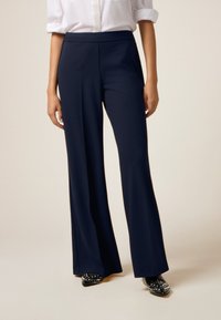Navy wijde broek met een gladde textuur en een hoge taille, voorzien van voorplooien en gecombineerd met versierde zwarte instappers.
