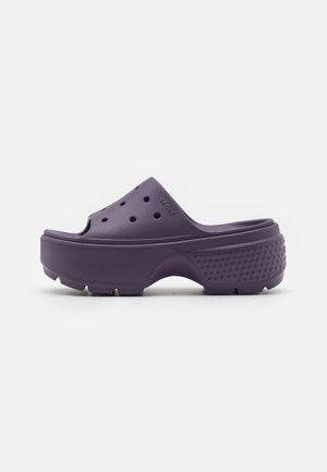 Sabots en caoutchouc violets avec des trous de ventilation et une semelle texturée. Caractéristiques d'un design arrondi et d'un dos surélevé pour un soutien supplémentaire.