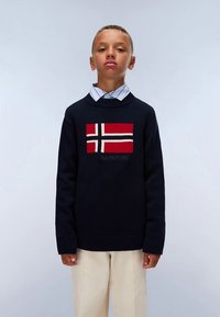 Temno modri pleteni pulover z norveško zastavo v rdeči, beli in črni barvi. Rebrasti manšeti in spodnji rob. Nošen čez srajco s ovratnikom in črtami.