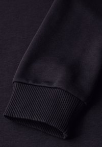 Schwarzes Langarmkleidungsstück mit gerippten Ärmelabschlüssen. Hergestellt aus einem glatten, blickdichten Stoff mit gleichmäßiger Textur.