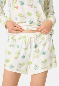 Kort pyjamasbyxor i vit tyg med ett repetitivt mönster av cocktails, limer och suckulenter. Har resårmidja med dragsko.