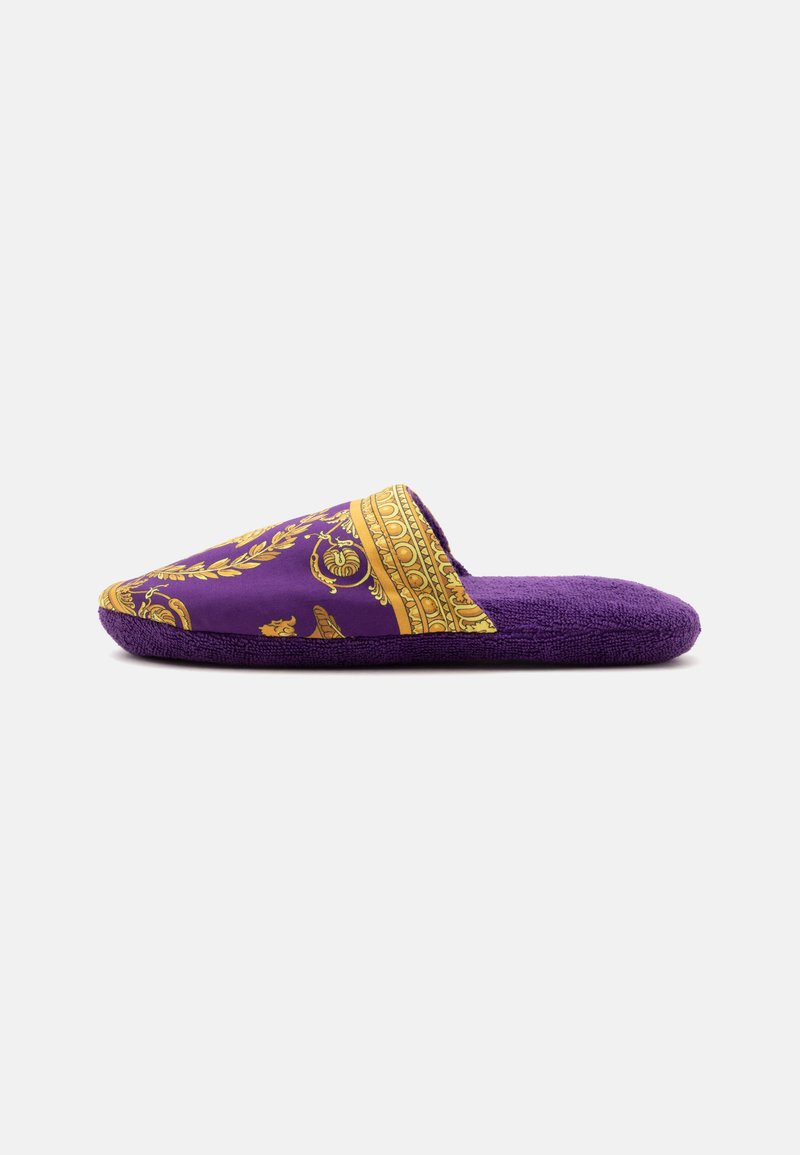Μωβ παντόφλα τύπου slip-on με χρυσό διακοσμητικό σχέδιο στο επάνω μέρος και μαλακή υφή στην σόλα, εμφανίζεται από το πλάι σε λευκό φόντο.