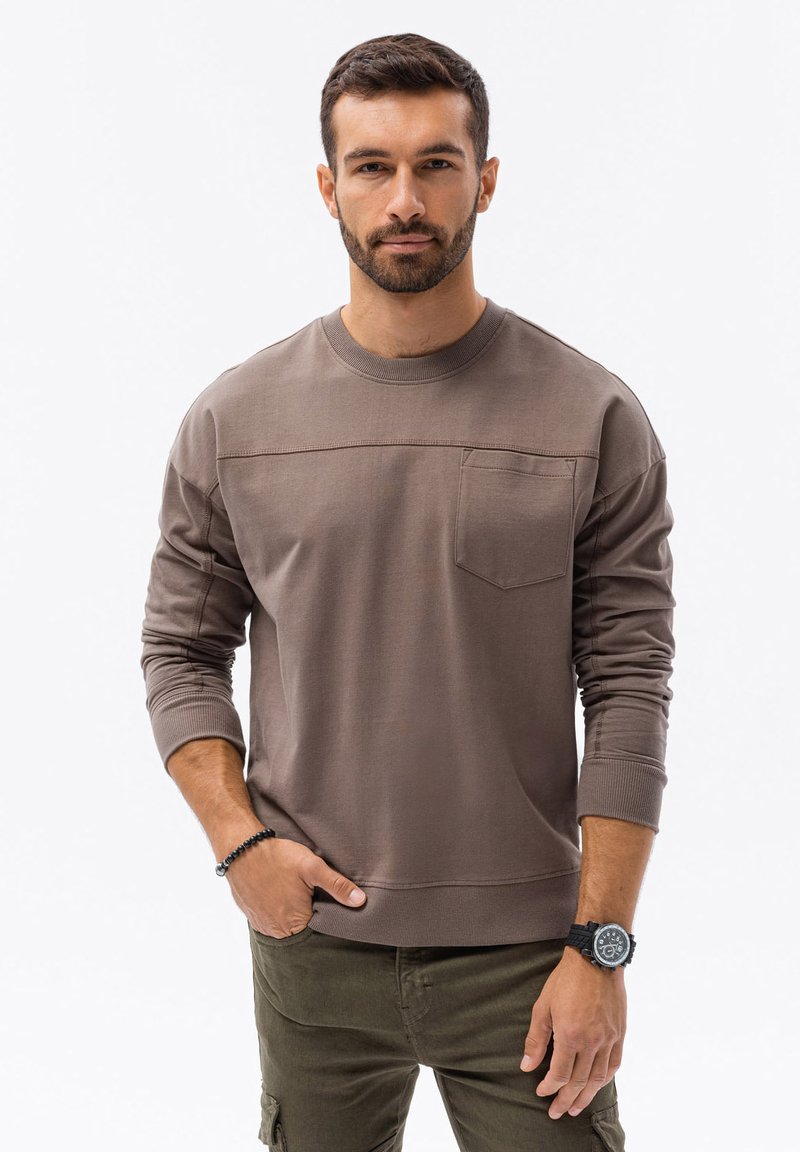 Hnědá mikina s dlouhými rukávy a kulatým výstřihem, která má náprsní kapsu a žebrované manžety. Hladký povrch s kontrastním prošíváním.