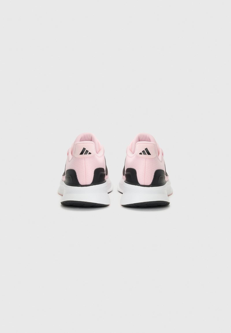Un paio di scarpe atletiche rosa e nere con suole bianche viste da dietro su uno sfondo bianco semplice.