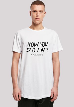 White cotton t-shirt with short sleeves featuring black text reading "HOW YOU DOIN'?" and "FRIENDS" below, relaxed fit.