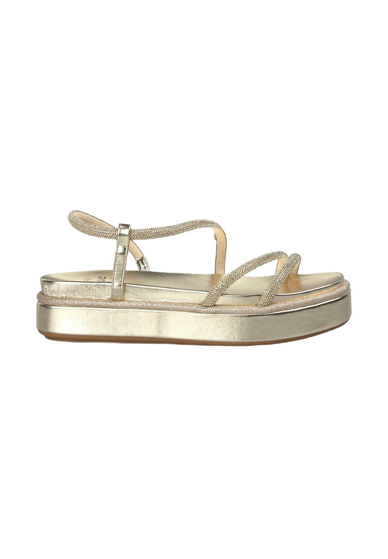 Sandales compensées dorées en métal avec des brides entrecroisées, texture lisse et semelle plate. Présente un léger éclat et une bride cheville sécurisée.
