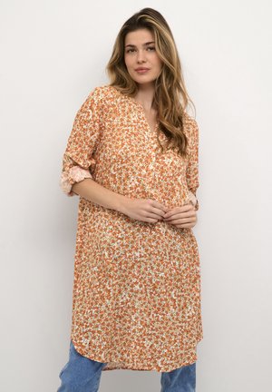 Tunica in stampa floreale arancione e crema, con scollo a V e maniche arrotolate. Tessuto leggero con vestibilità rilassata e orlo curvo.