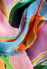 Tissu coloré froissé avec des motifs floraux et géométriques abstraits dans des tons pastel de rose, bleu, vert, orange et noir.