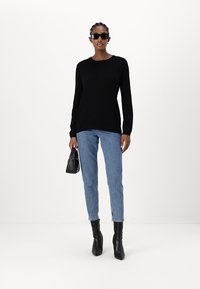 Black long-sleeve top, light blue jeans, black ankle boots, and small black handbag. Smooth texture, fitted design, and simple color palette.
