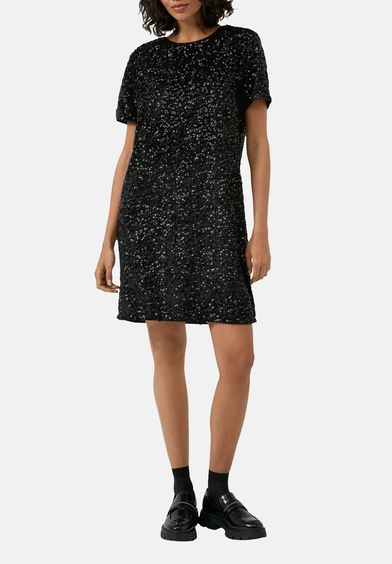 Czarna sukienka z cekinami, o okrągłym dekolcie i krótkich rękawach, cechująca się luźnym krojem i teksturowaną powierzchnią. Do tego czarne mokasyny.