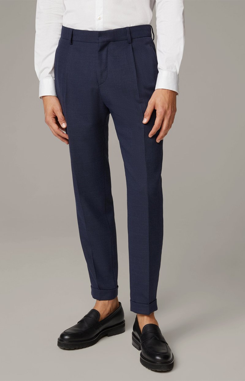 Marineblå skræddersyede bukser med et elegant design, der har frontfolder og opfoldede manchetter. Bæret med sorte slip-on sko.