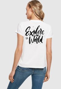 Weißes T-Shirt mit kurzen Ärmeln, das mit schwarzem Text "Erkunde die Welt" und grafischen Akzenten auf der Rückseite versehen ist. Weiches Baumwollmaterial, lockere Passform.