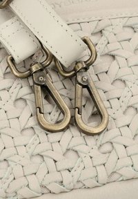 Bolso de cuero tejido en gris claro con doble clip de latón y correas de cuero blanco. Presenta intrincados detalles de tejido y costura.