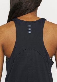 Černý sportovní top bez rukávů s designem na zádech racerback, s texturovanou panely na zádech a jemnými reflexními prvky podél páteře.